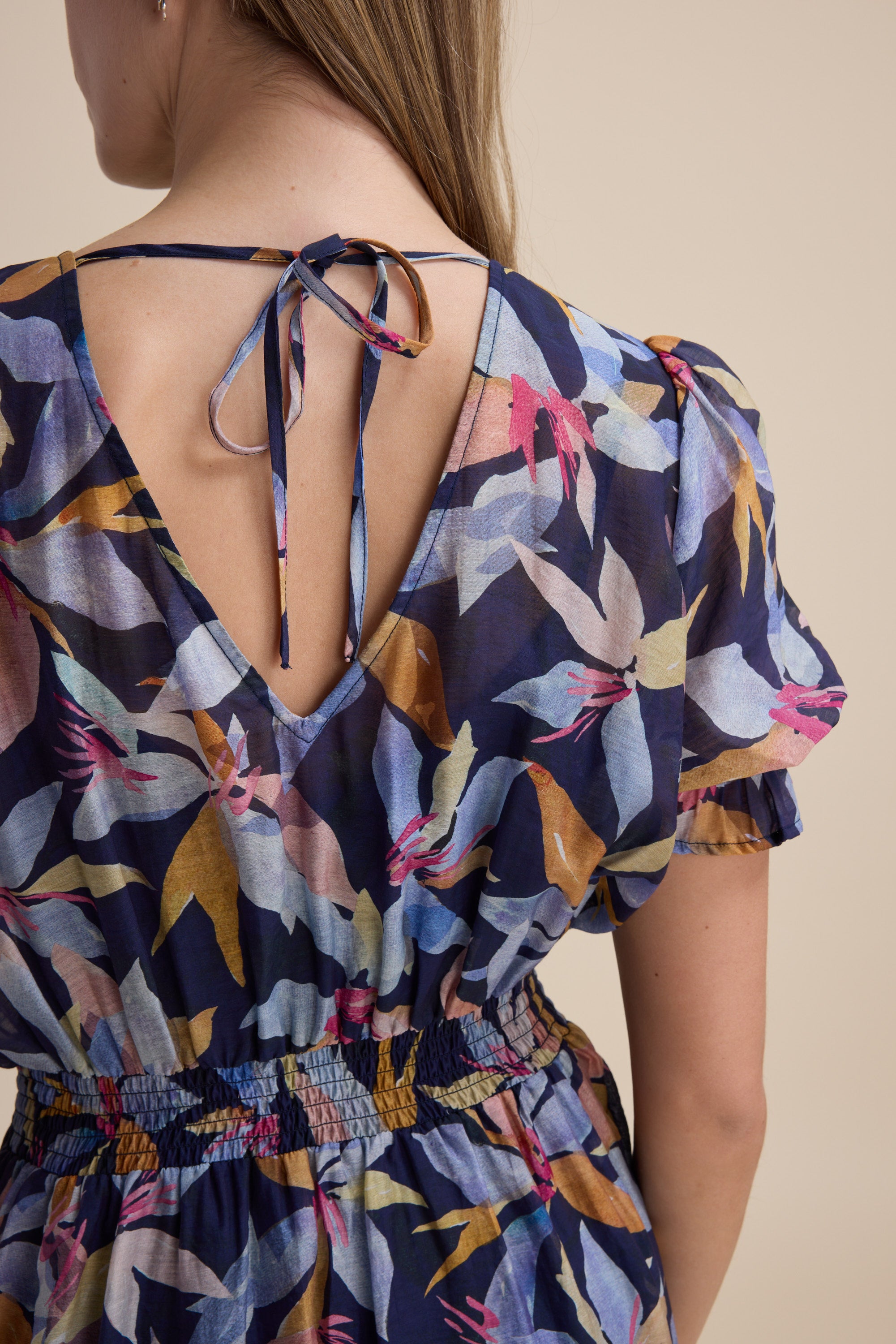 Woman seen from behind in Max's Ava Gather Waist Dress, blue floral midi with puff sleeves.
