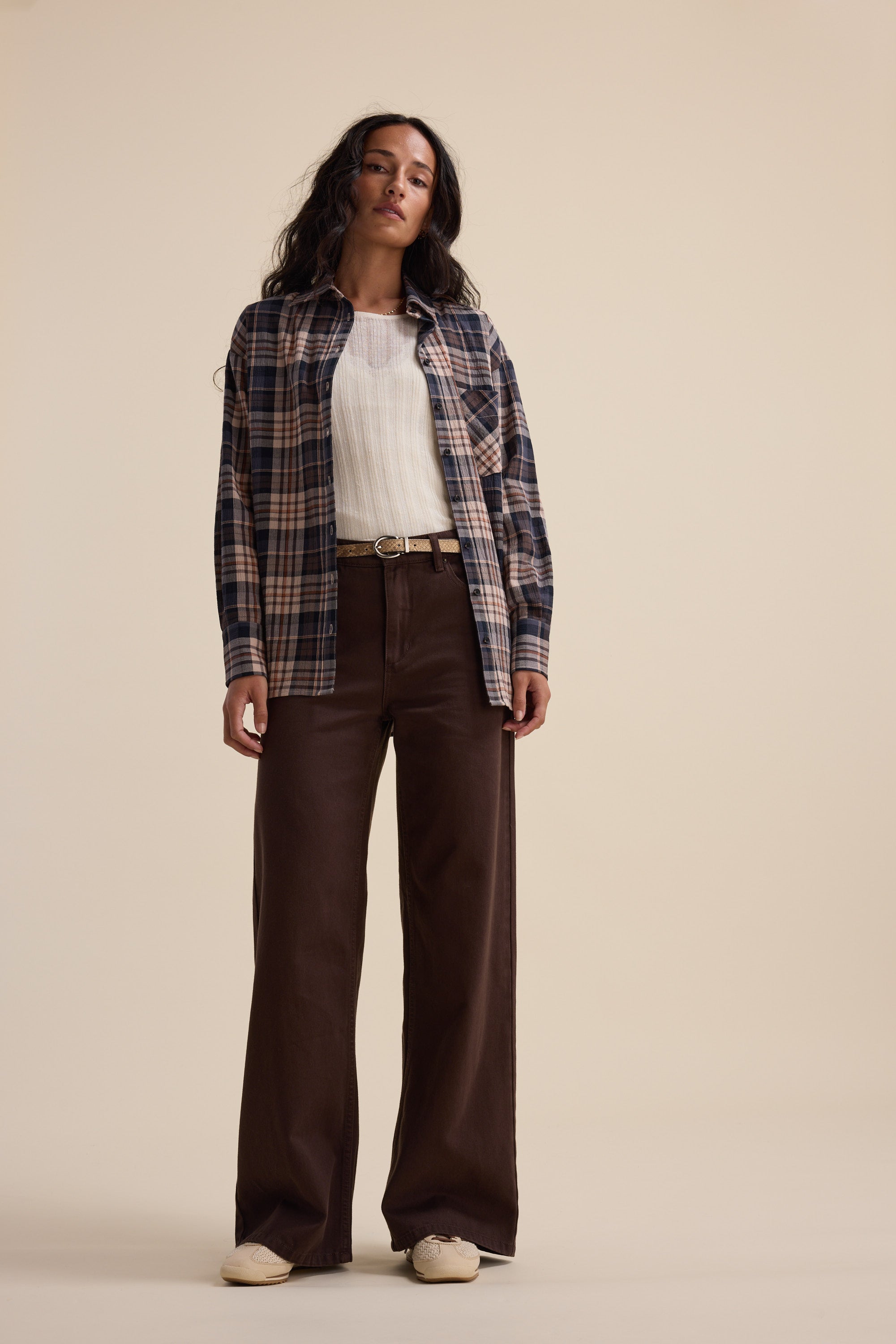 Woman in plaid shirt, white top, Max Alaska Wide Leg Jeans, and white shoes on beige background.