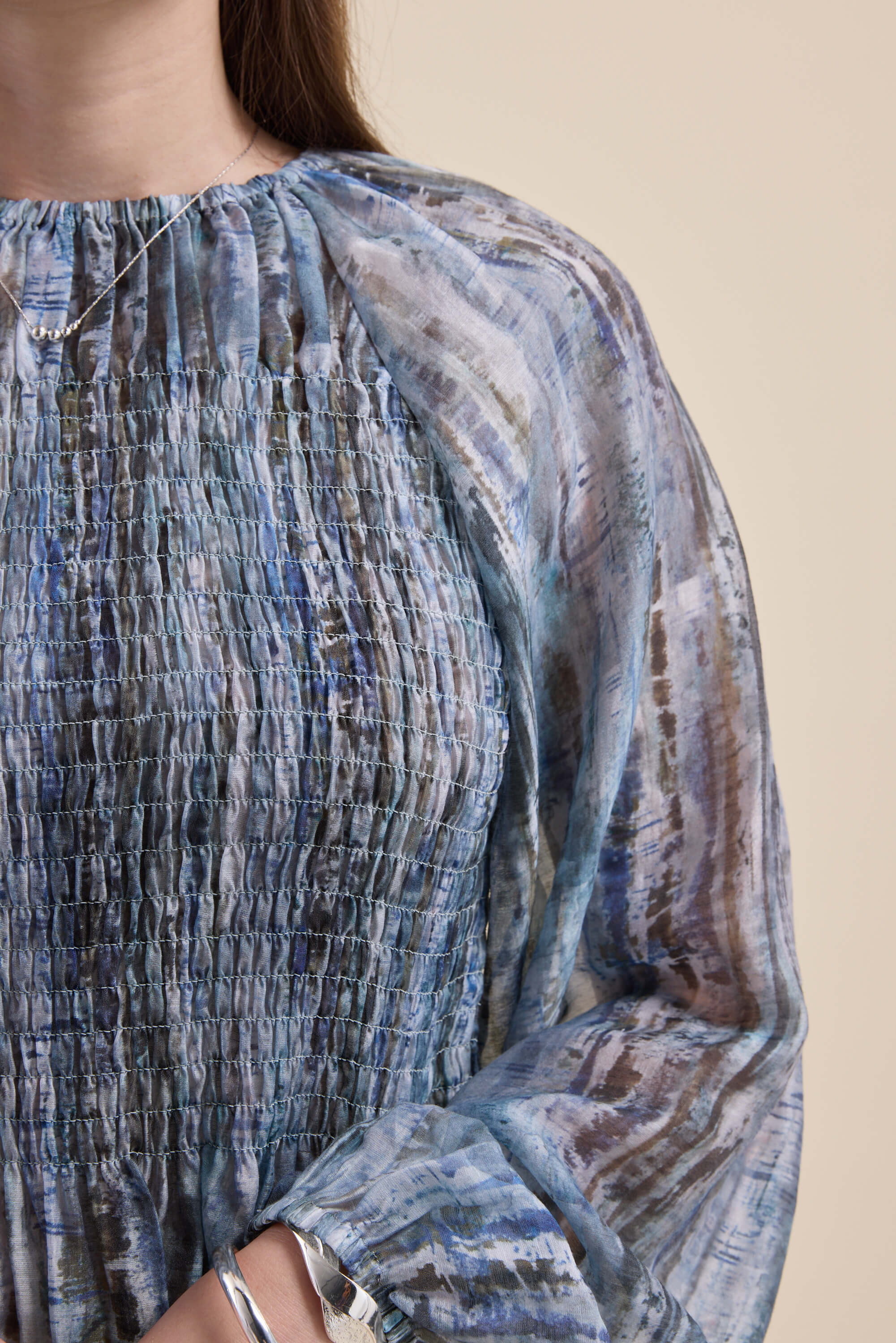 Woman in the Max Mitch Shirred Top, blue patterned with puff sleeves, shown from shoulders down.