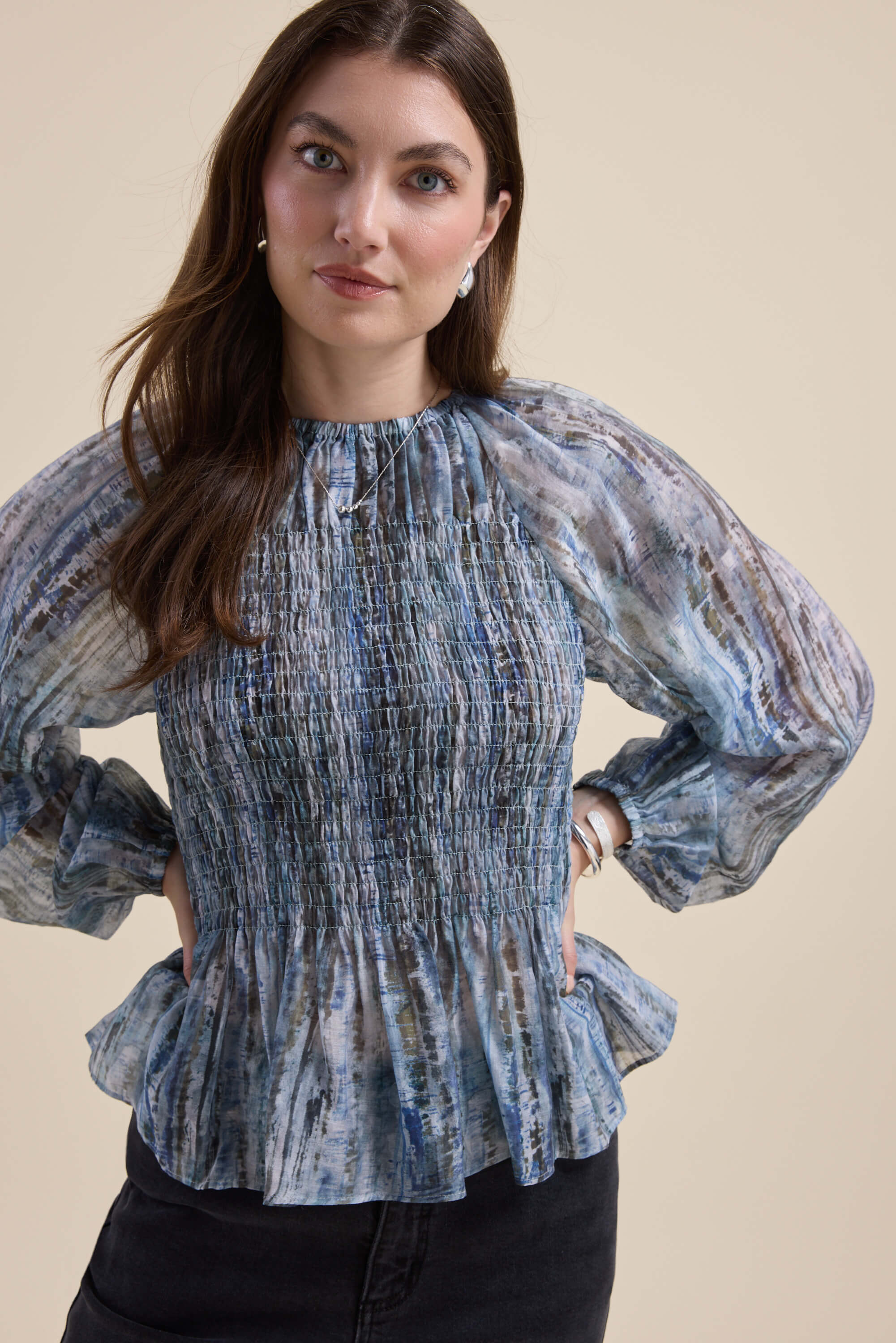 Woman in the Max Mitch Shirred Top, a blue sheer blouse with puff sleeves, and black pants.