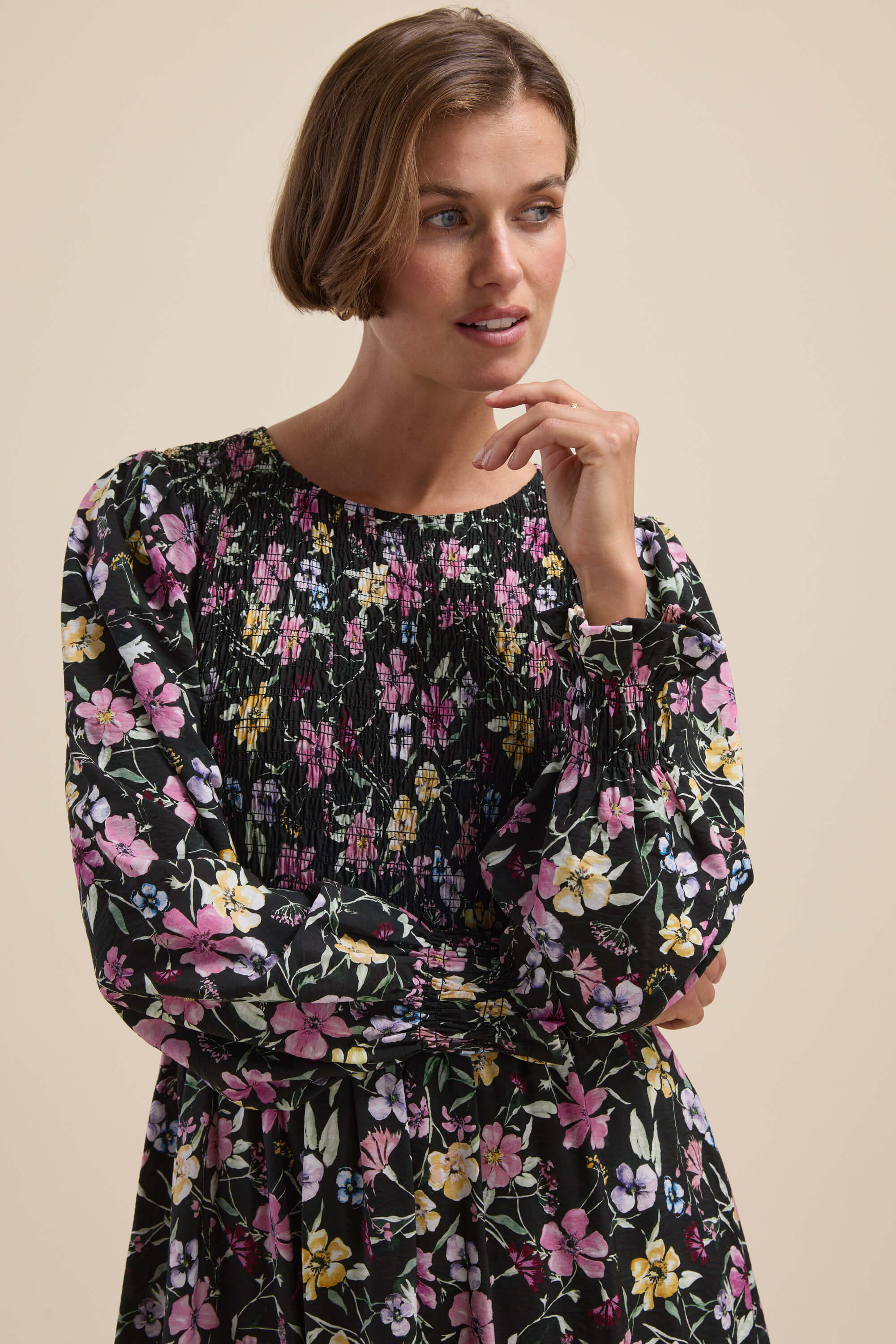 Woman in the Max Brooke Shirred Long Sleeve Dress with pink, yellow, and white florals.