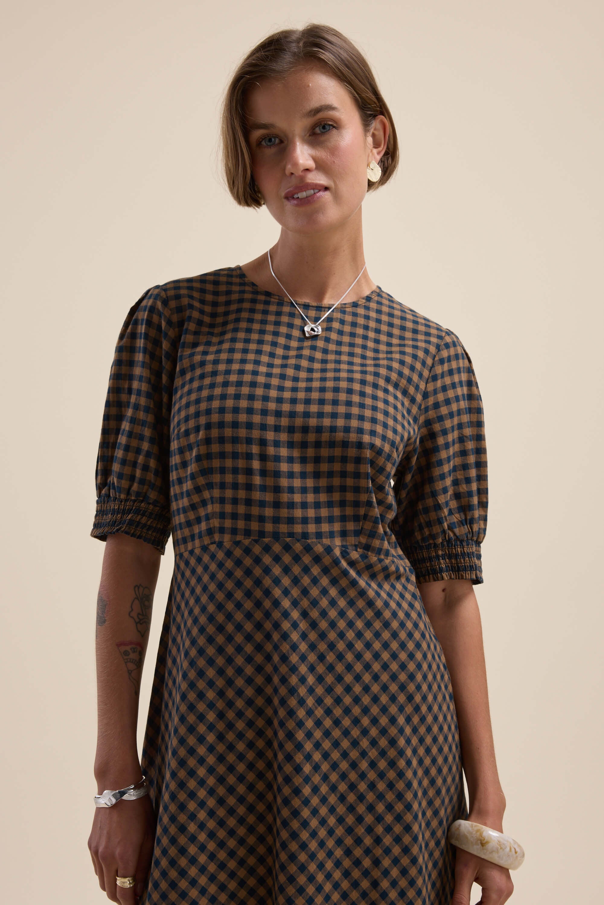 Model wears the Max Lucy Bias Cut Dress in checkered print against a plain beige background.