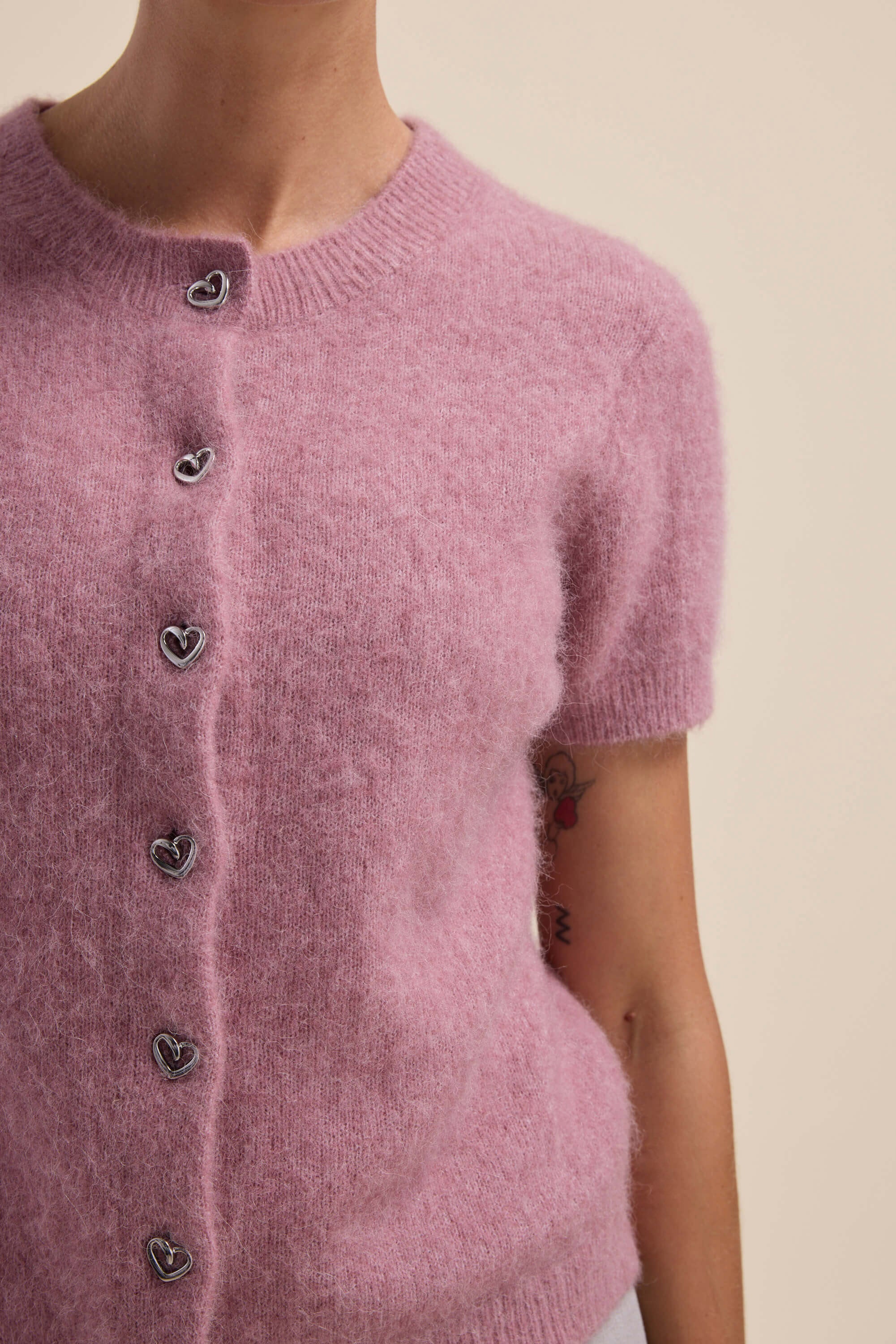 Person wears Max Adelaide Luxe Whisper Short Sleeve Cardigan in Pink Bloom with heart buttons.