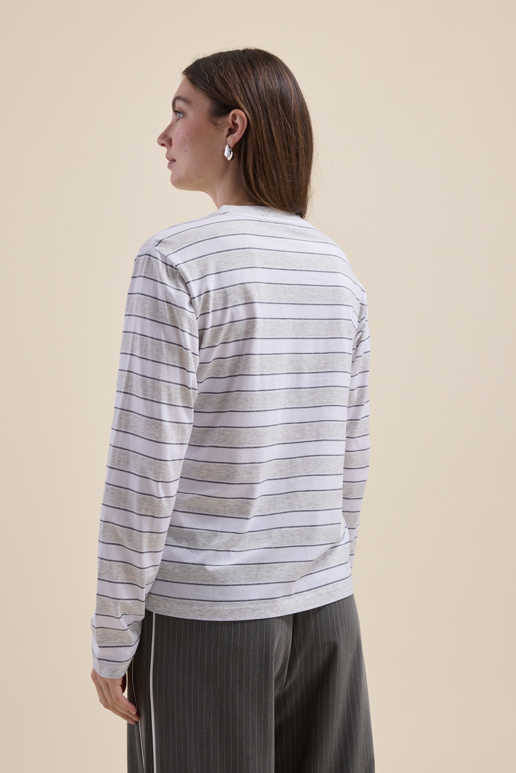 Woman in Max Carmen Long Sleeve Stripe Tee, facing away against a beige background.