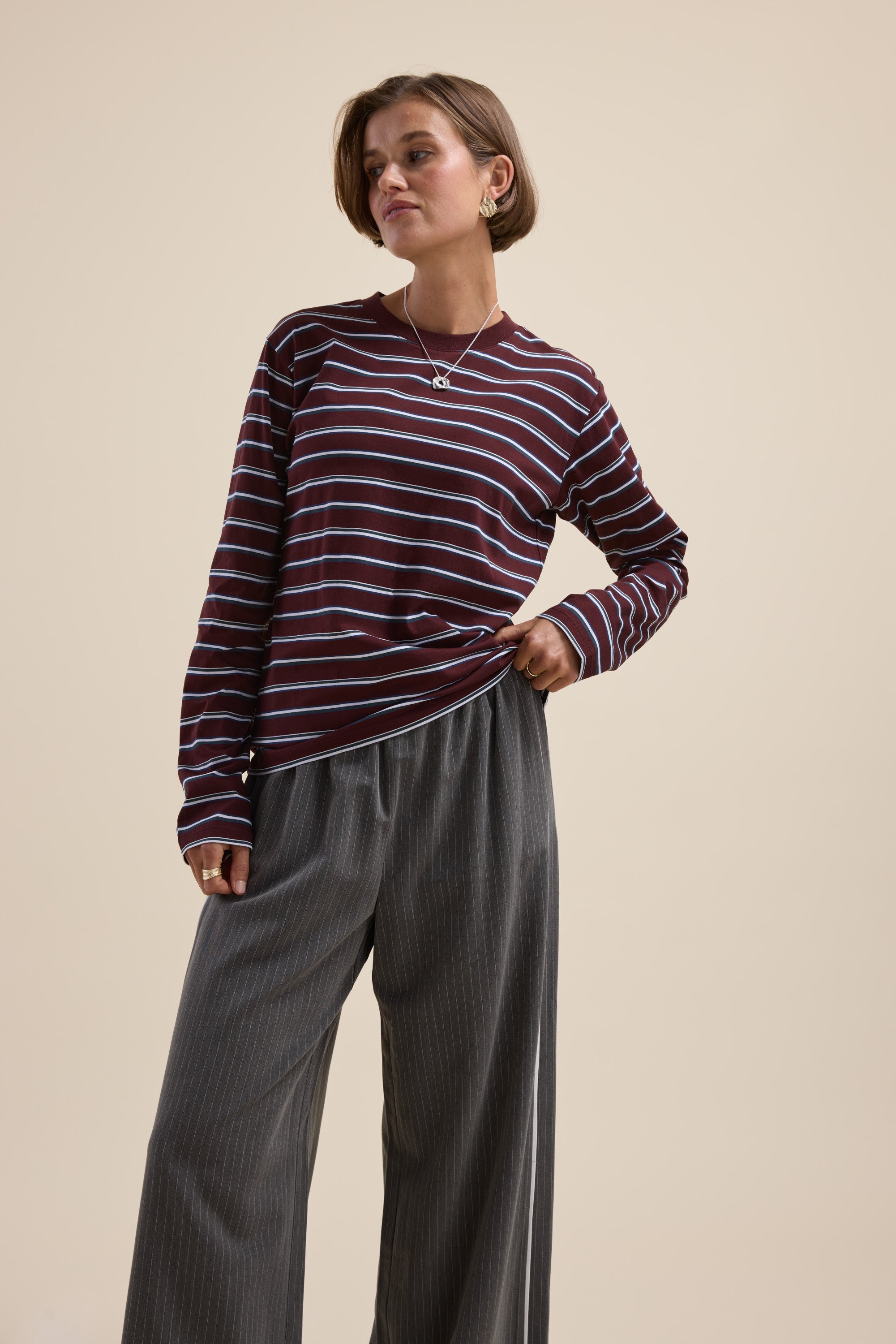 Woman wears Max Carmen Long Sleeve Stripe Tee with gray wide-leg pants, standing confidently.