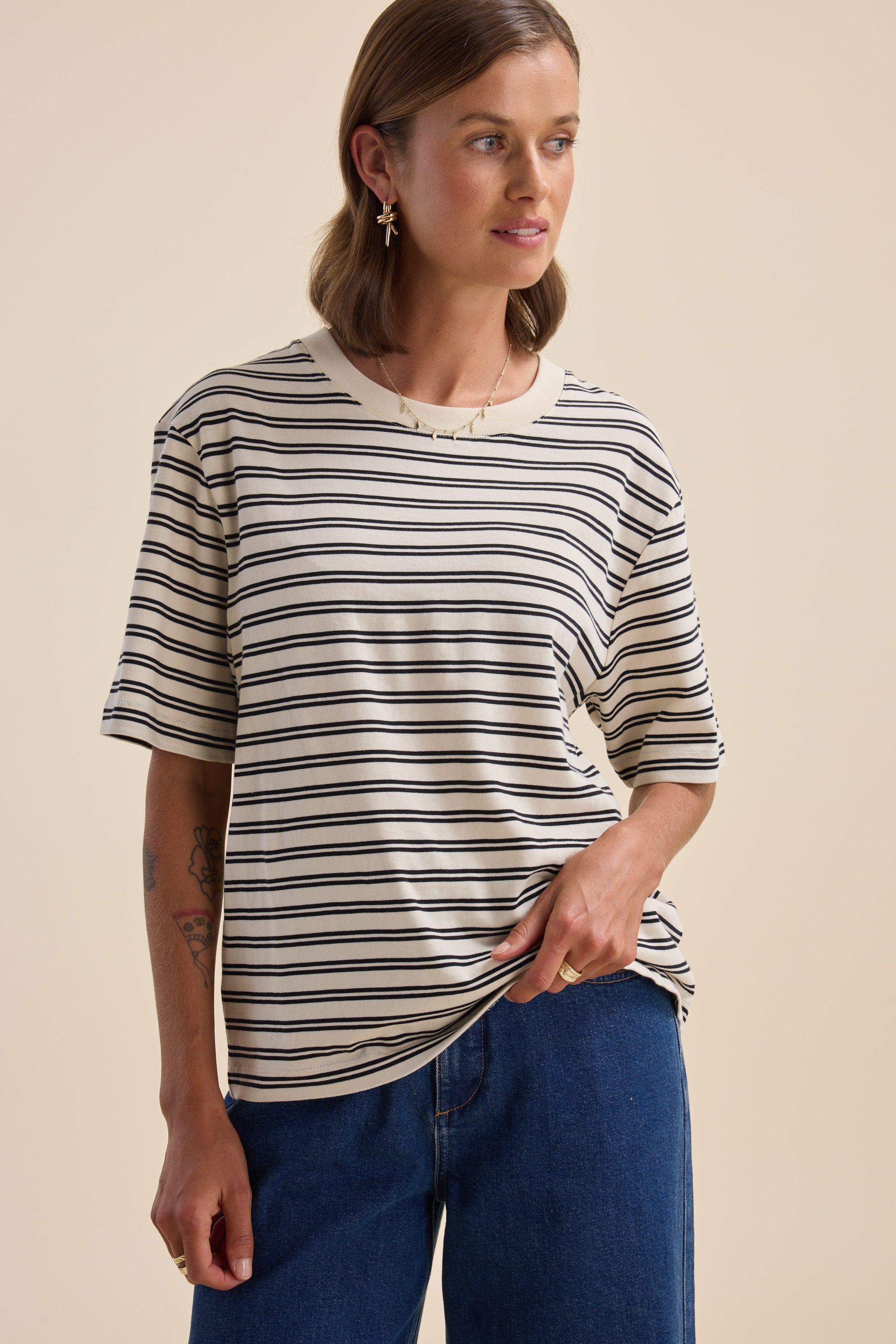 Woman in Max Charmaine Organic/Pima Cotton Tee and blue jeans, against a neutral background.