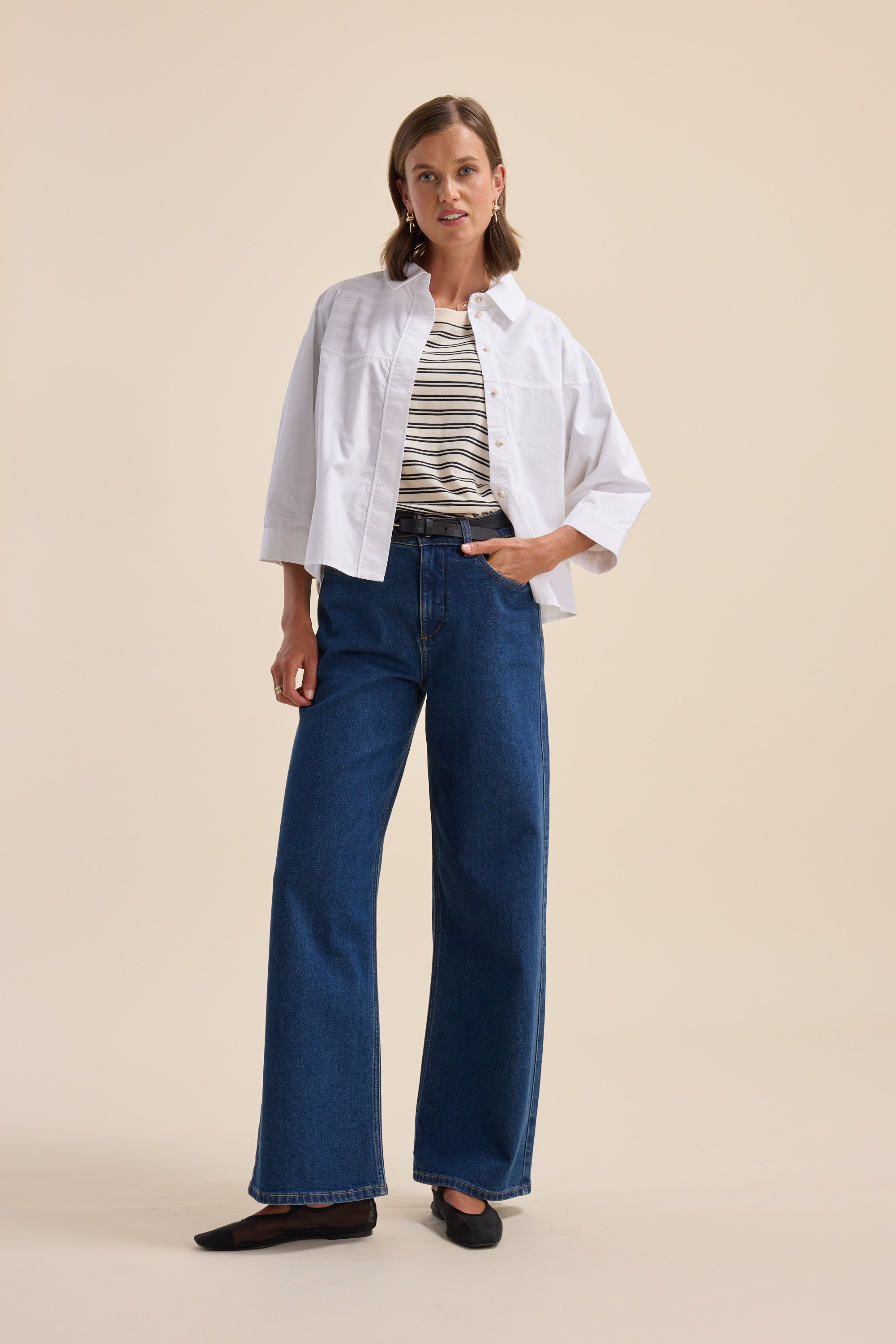 Woman in a Max Charmaine Organic/Pima Cotton Tee, striped top, wide-leg jeans, and black flats.