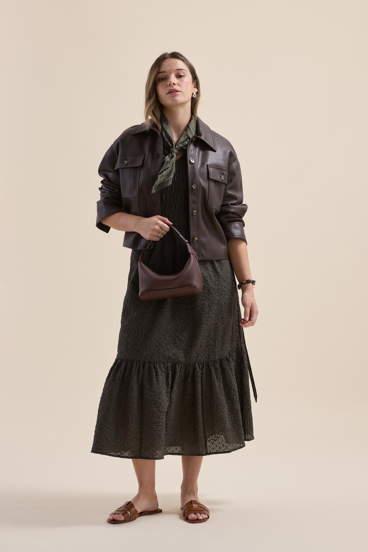 Woman in Elementary Shirred Bodice Dress, brown jacket, purse, sandals, and green scarf.