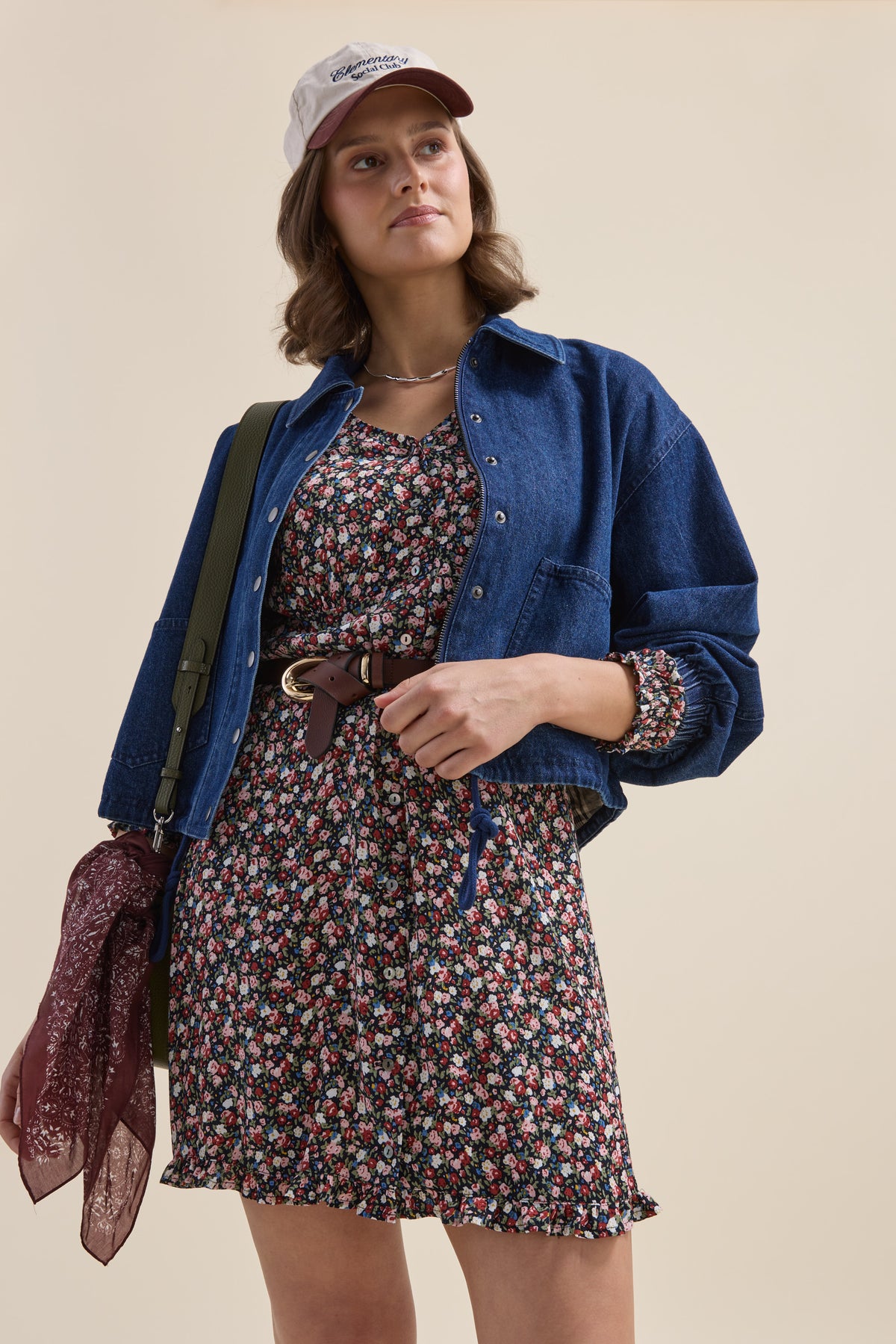 Woman in an Elementary Button Front Dress, denim jacket, cap, crossbody bag, and scarf.