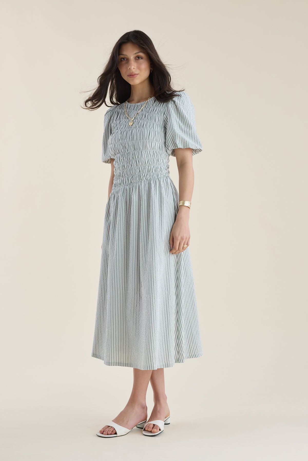 Woman in a Max Talia Shirred Detail Midi Dress with puff sleeves stands against a beige background.