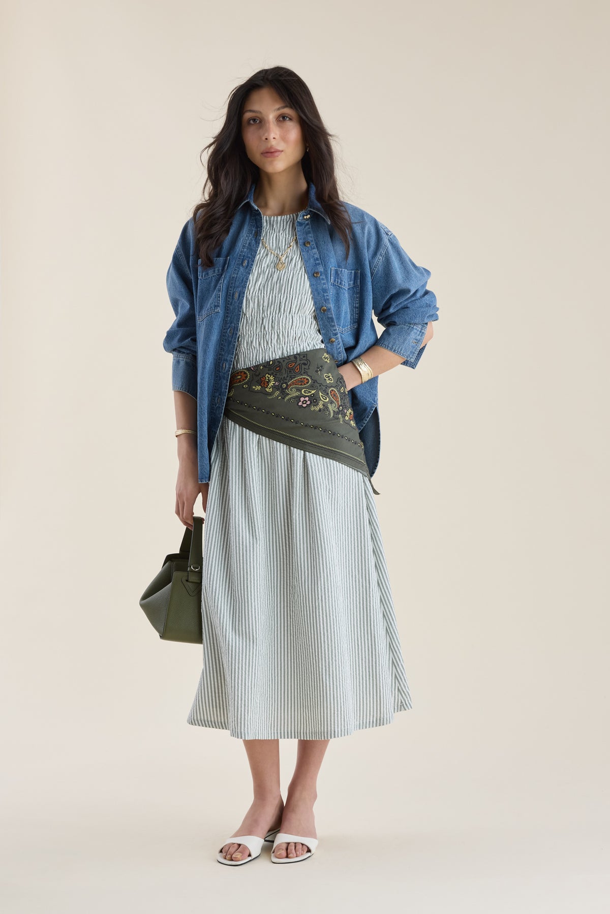 Woman in a Max Talia Shirred Detail Midi Dress, denim shirt, crossbody bag, and green purse.