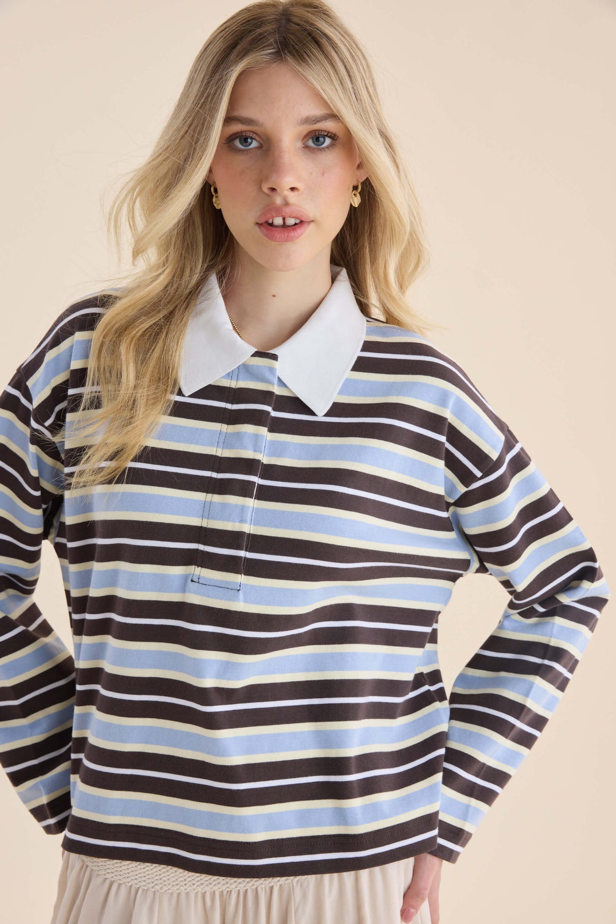 Woman in Elementary Polo Top by Elementary stands hands on hips, relaxed silhouette.