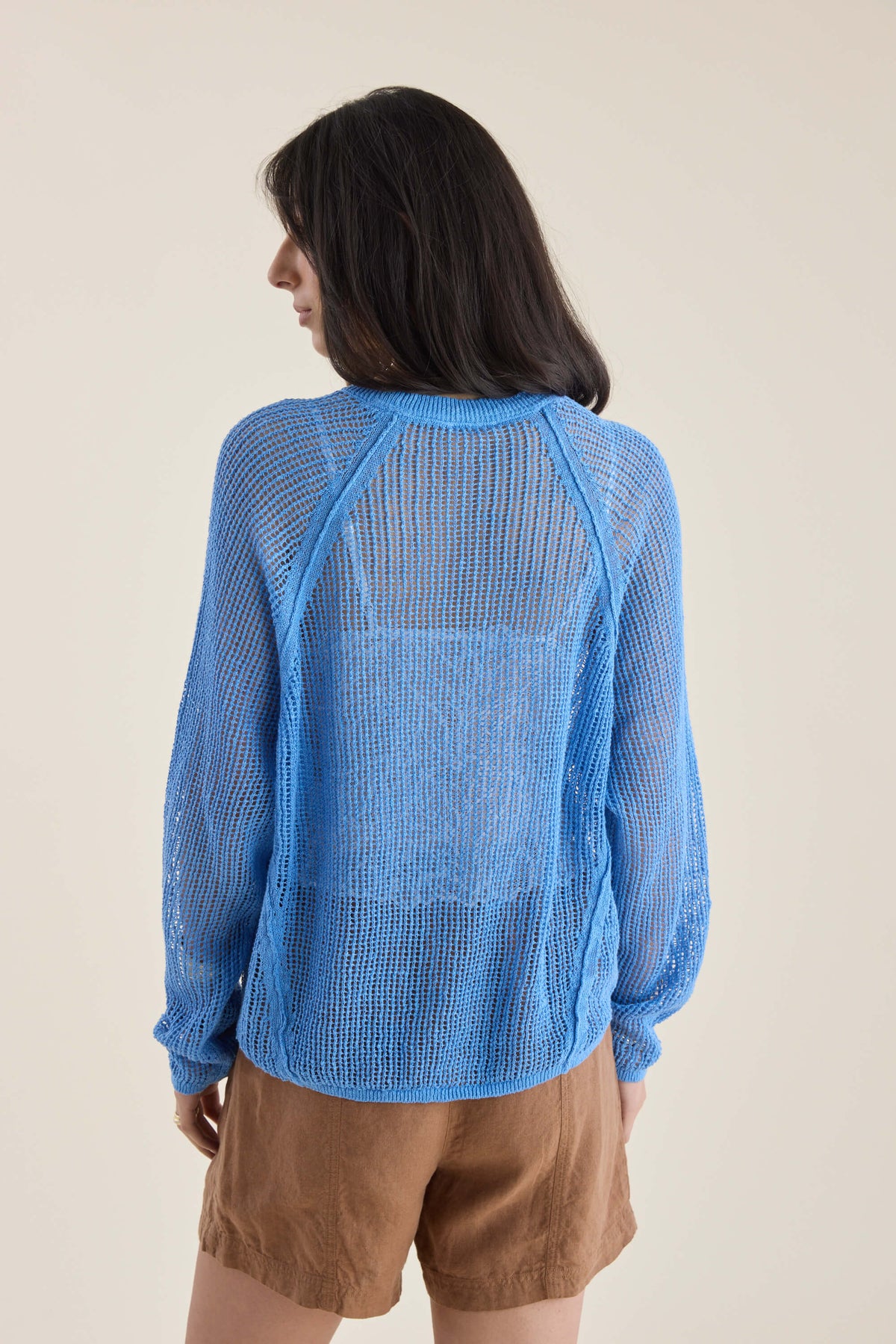 Woman in Elementary Linen Knit Detail Sweater (blue, sheer) and brown shorts, shown from back.
