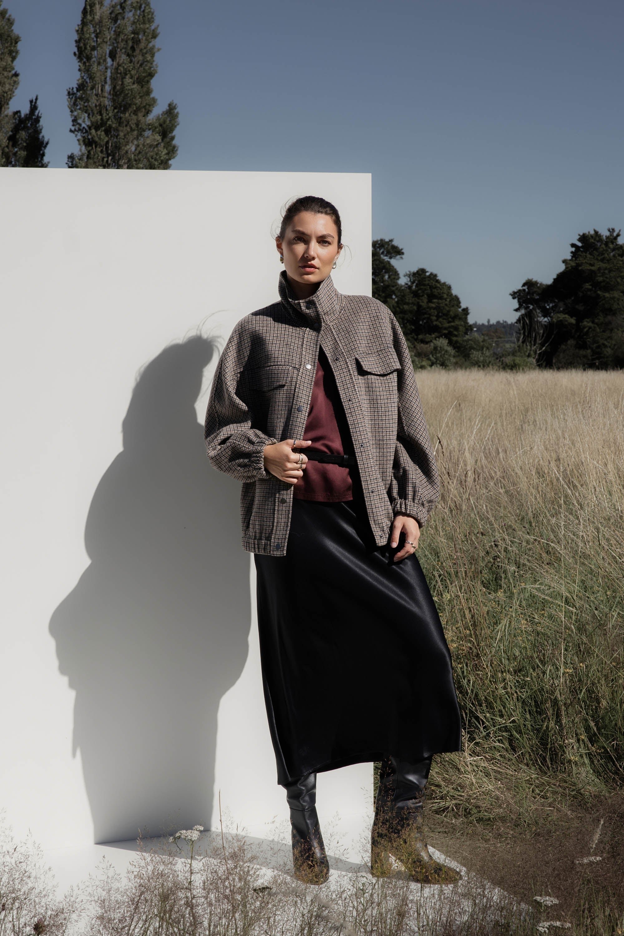 Woman in The Perfect Slip Skirt by Max stands by a white wall in a grassy field.