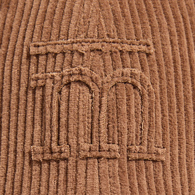Close-up of a brown corduroy fabric with an embroidered NZ double-arch design.