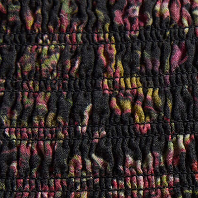 Close-up of NZ black fabric with colorful floral-like pattern and gathered, ruched texture.